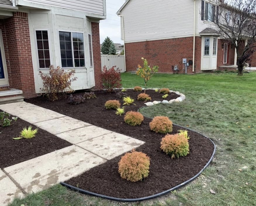 Mulch installation in the front garden with cobblestone, small shrubs and small trees