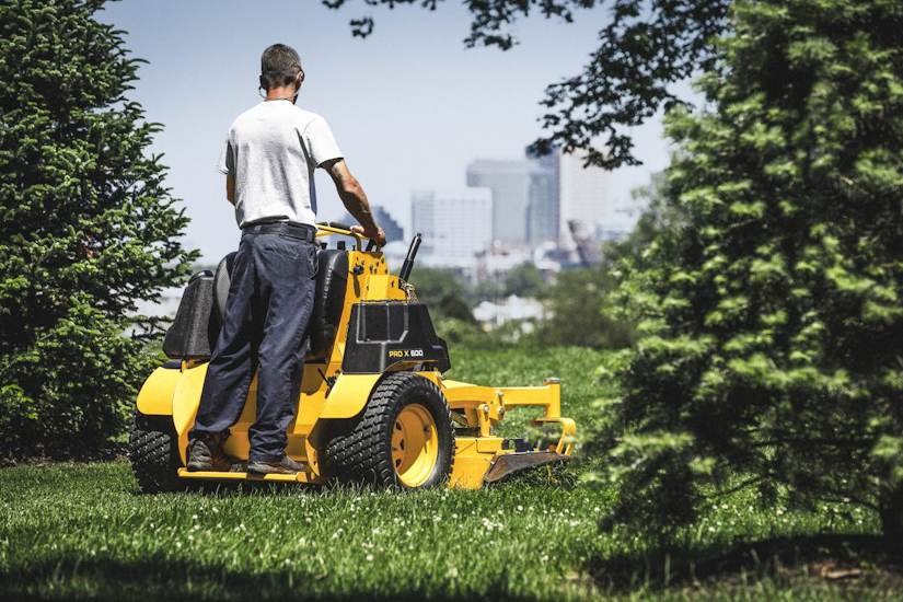 Landscaper cutting grass with a Cub Cadet stand on mower
